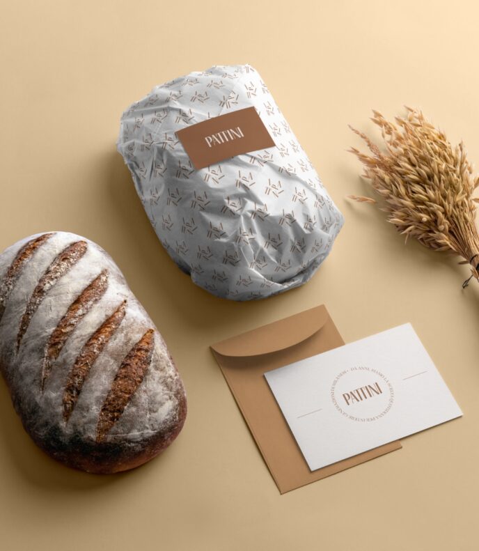 Una forma di pane, un sacchetto di carta per il pane e una cartolina di Pattini Milano.